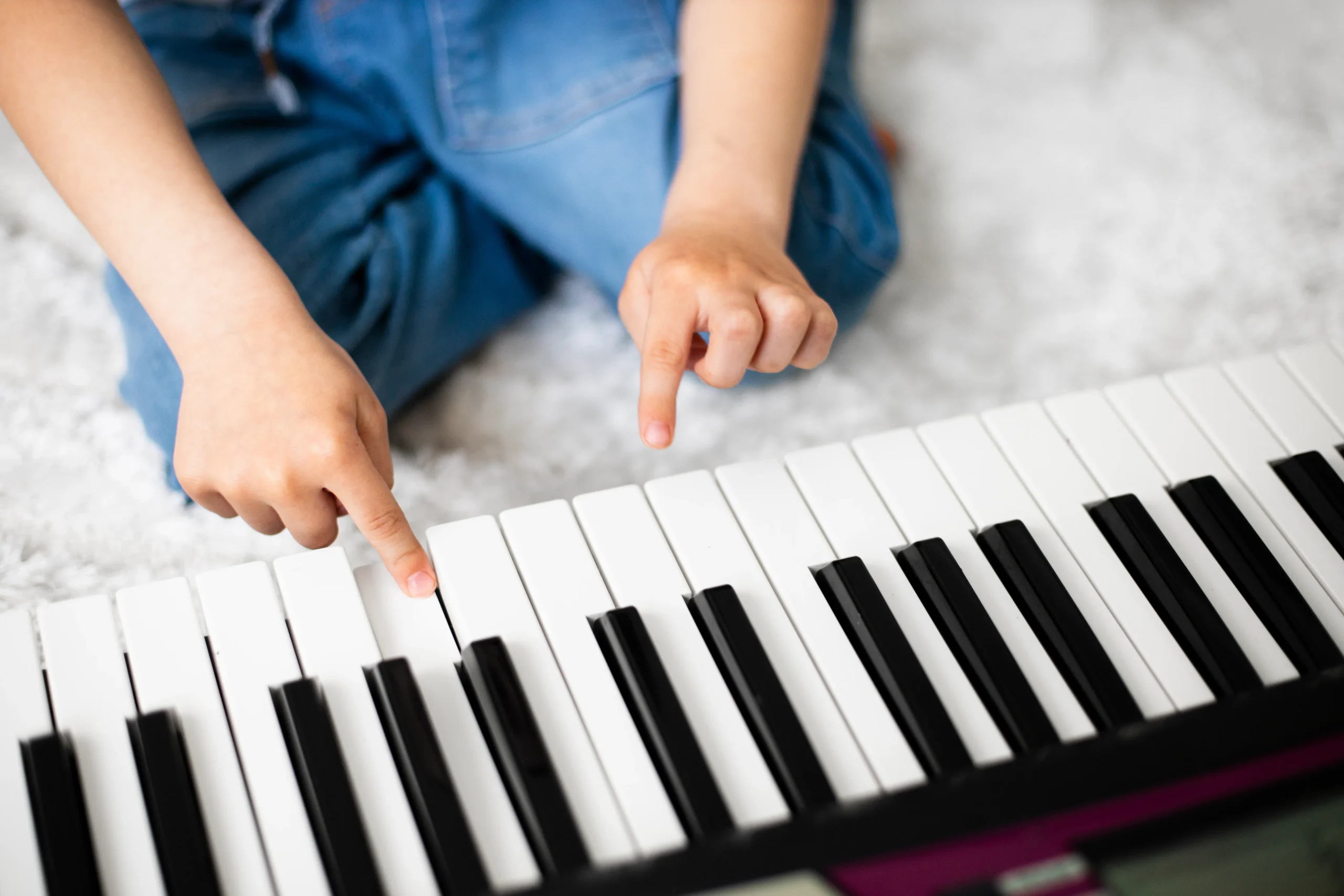 Child's hands playing simple piano melody with easy sheet music visible