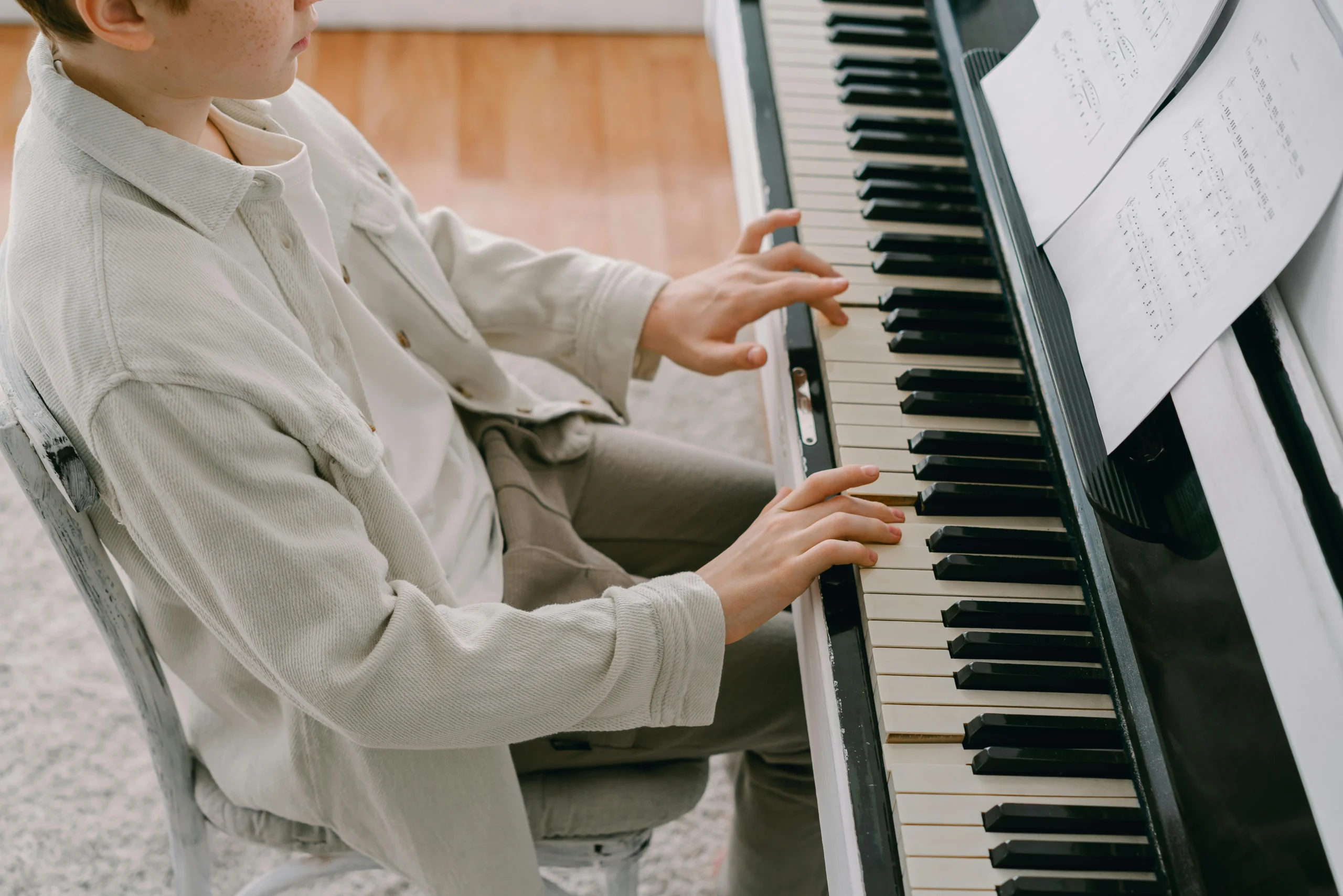 Beginner pianist reading easy sheet music while practicing on acoustic piano without teacher