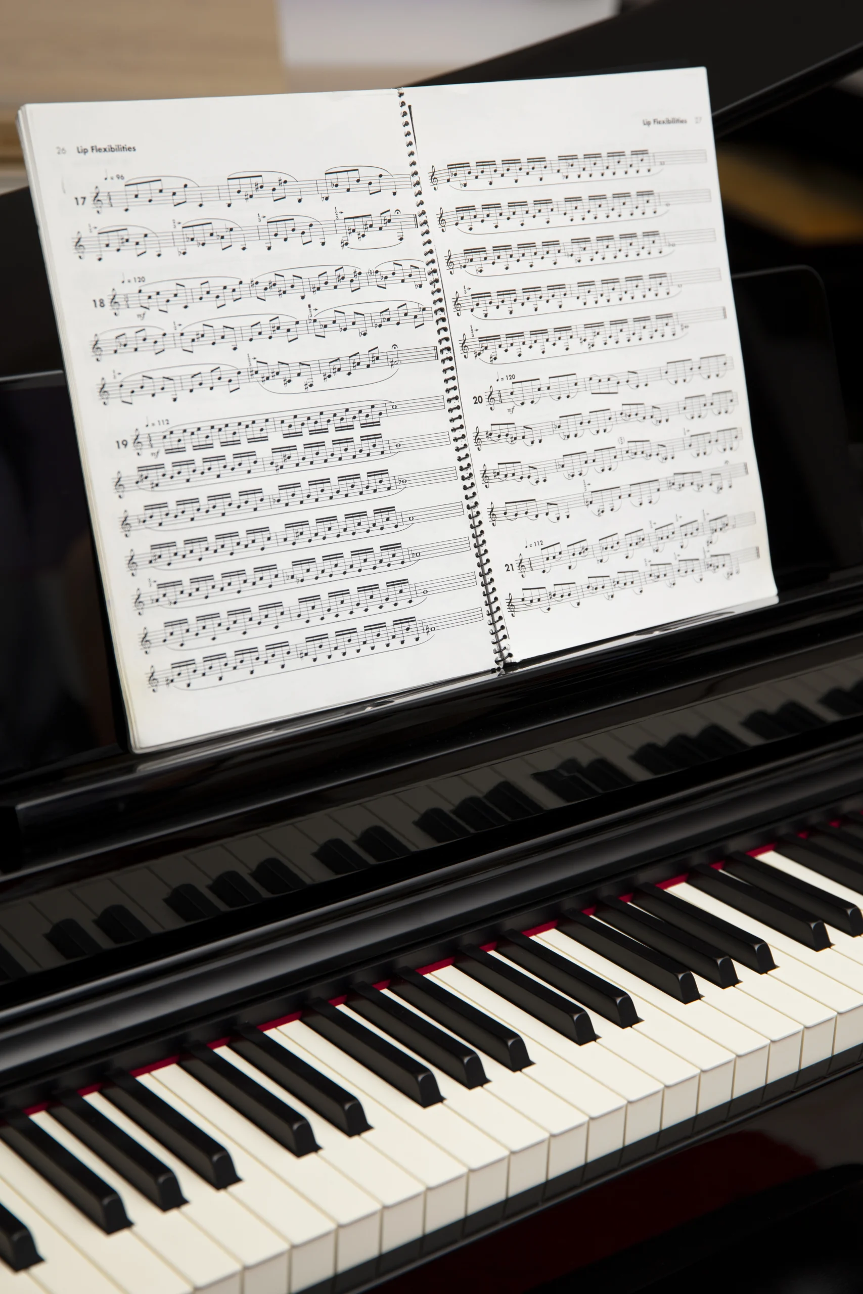 Popular pop piano sheet music downloads displayed on a tablet with piano keys in the background