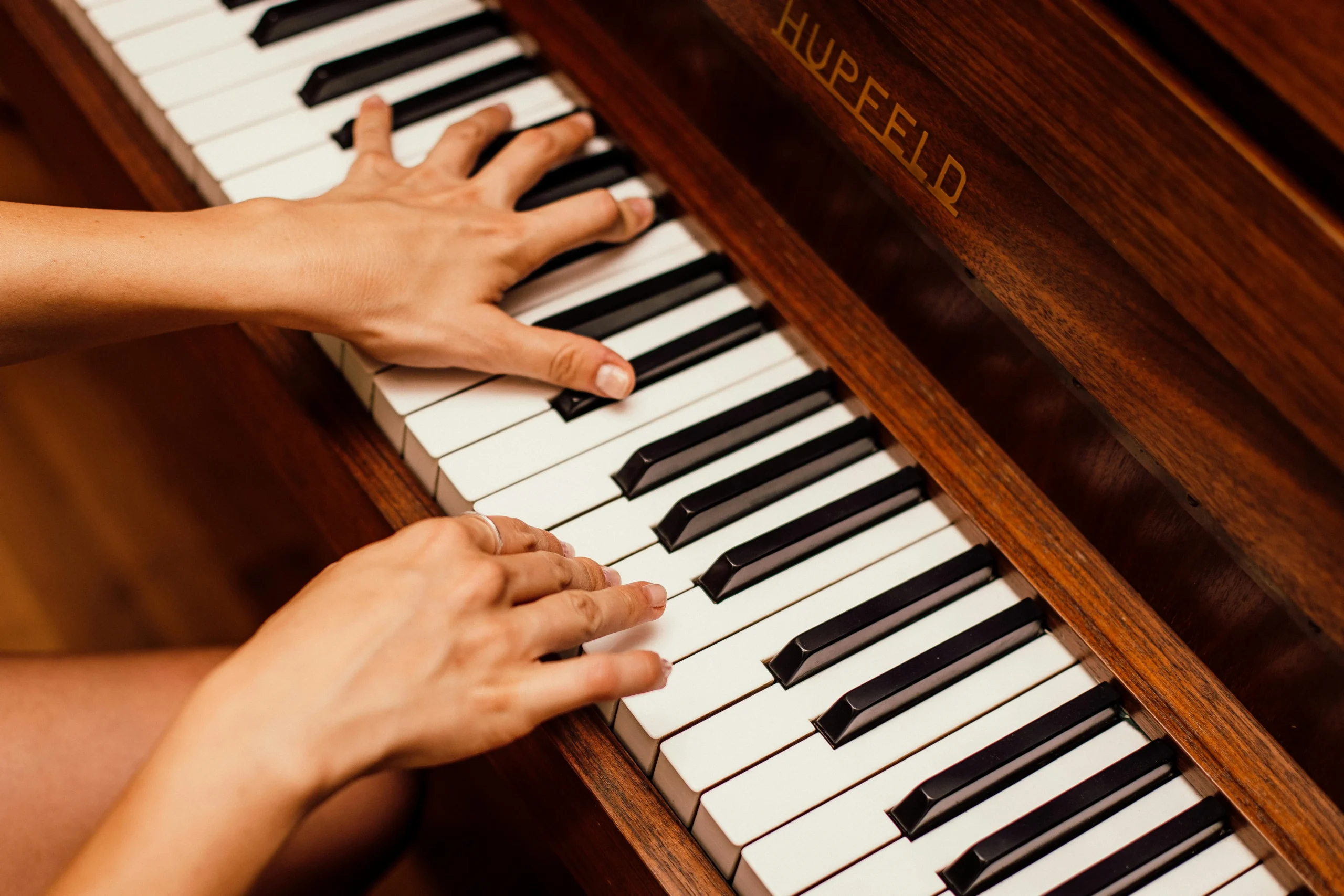 Popular piano sheet music on piano with hands playing keys