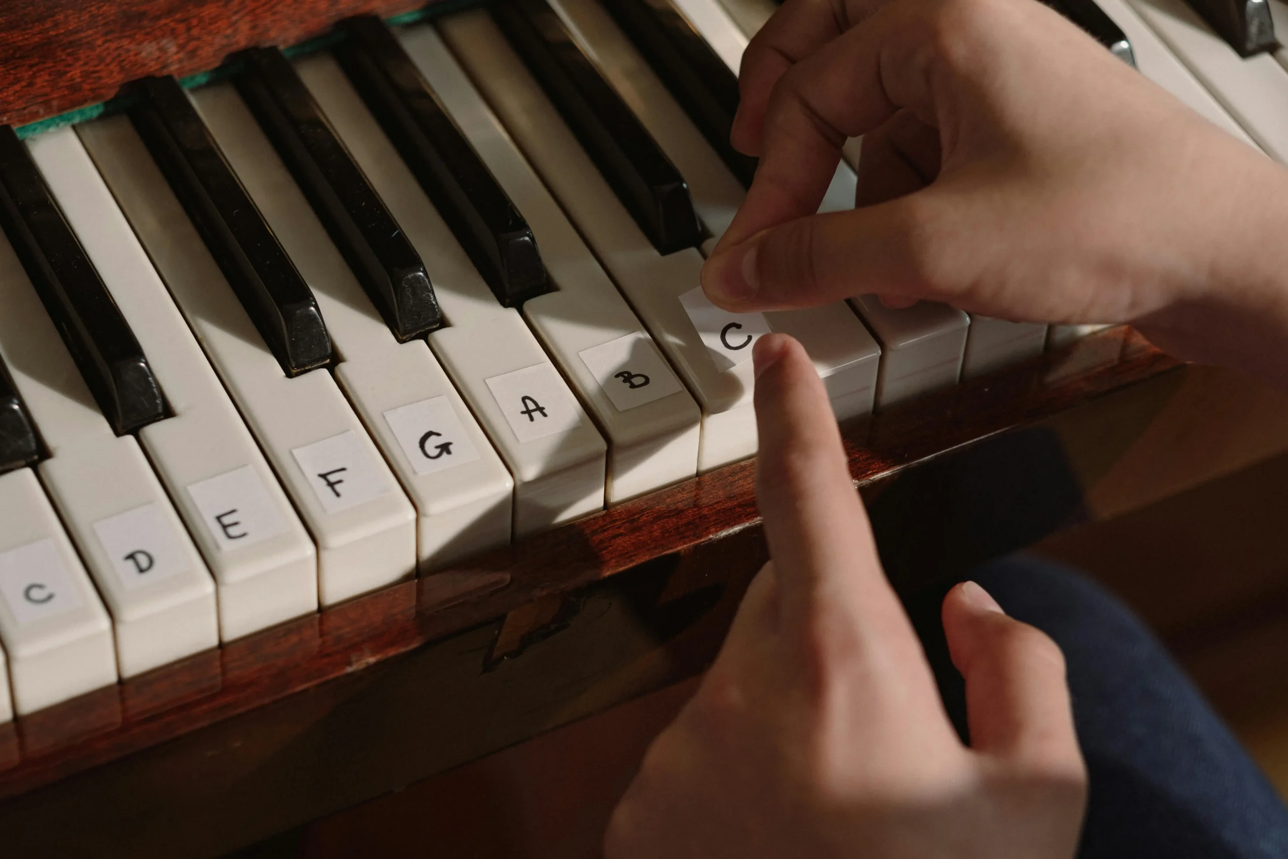 Beginner pianist practicing piano with labeled keys