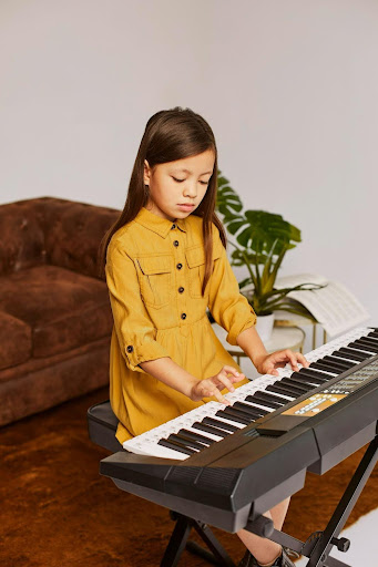 Young beginner piano practicing finger positions on keyboard with sheet music